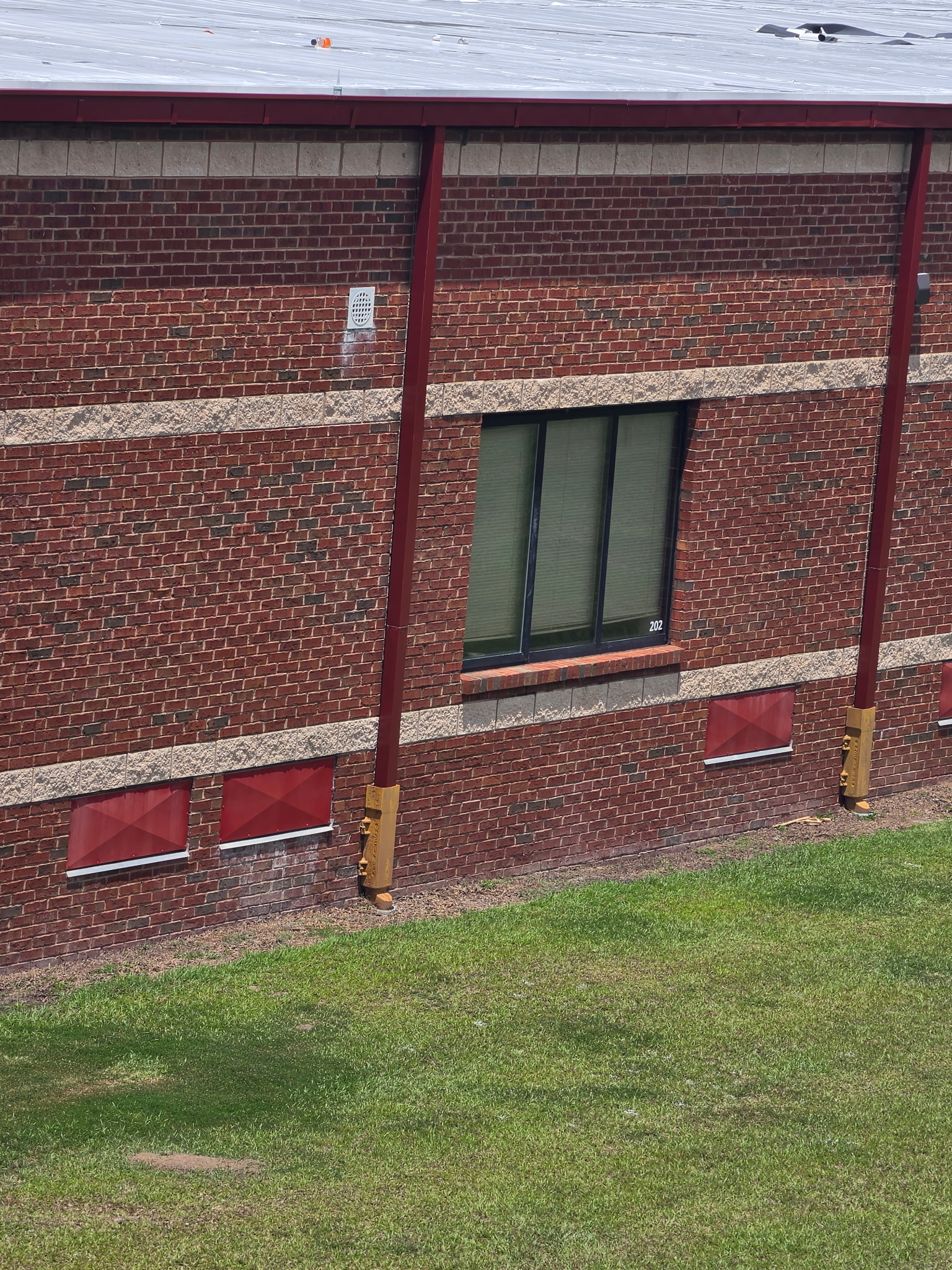 Exterior view of New Midway Middle School showing red steel column covers, window trim, and the finished perimeter metal fabricated by MPI Fabrication